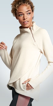 woman wearing a beige cozy karma sweater with a slight turtle neck zipper