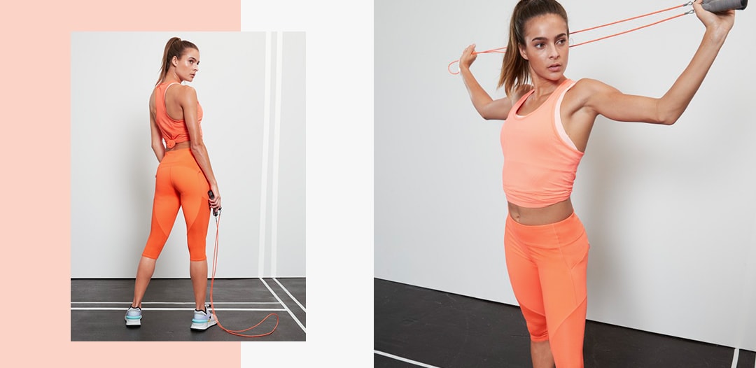 woman wearing orange contender capri and orange tank top stretching with a band