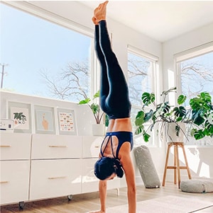 woman wearing athleta top and bottoms doing a hand stand